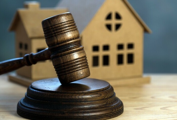 Gavel in front of a minature model of a house